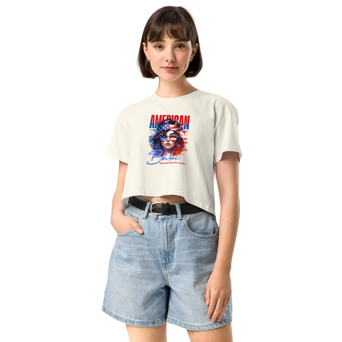 Woman wearing a white crop t-shirt with a graphic design and denim shorts on a white background