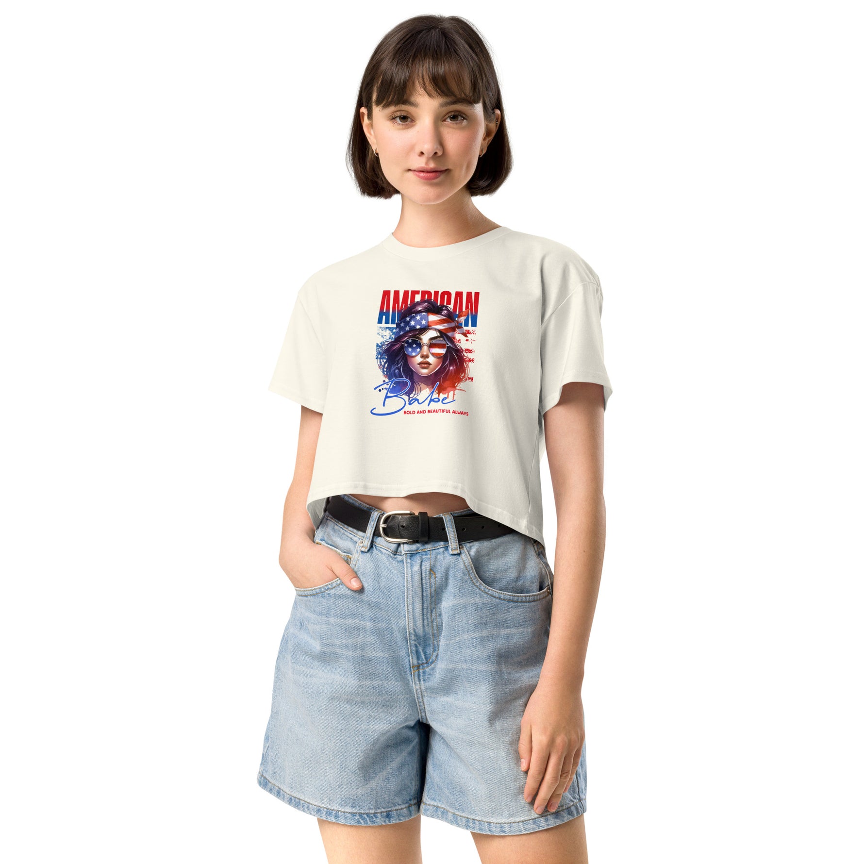 Woman wearing a white crop t-shirt with a graphic design and denim shorts on a white background