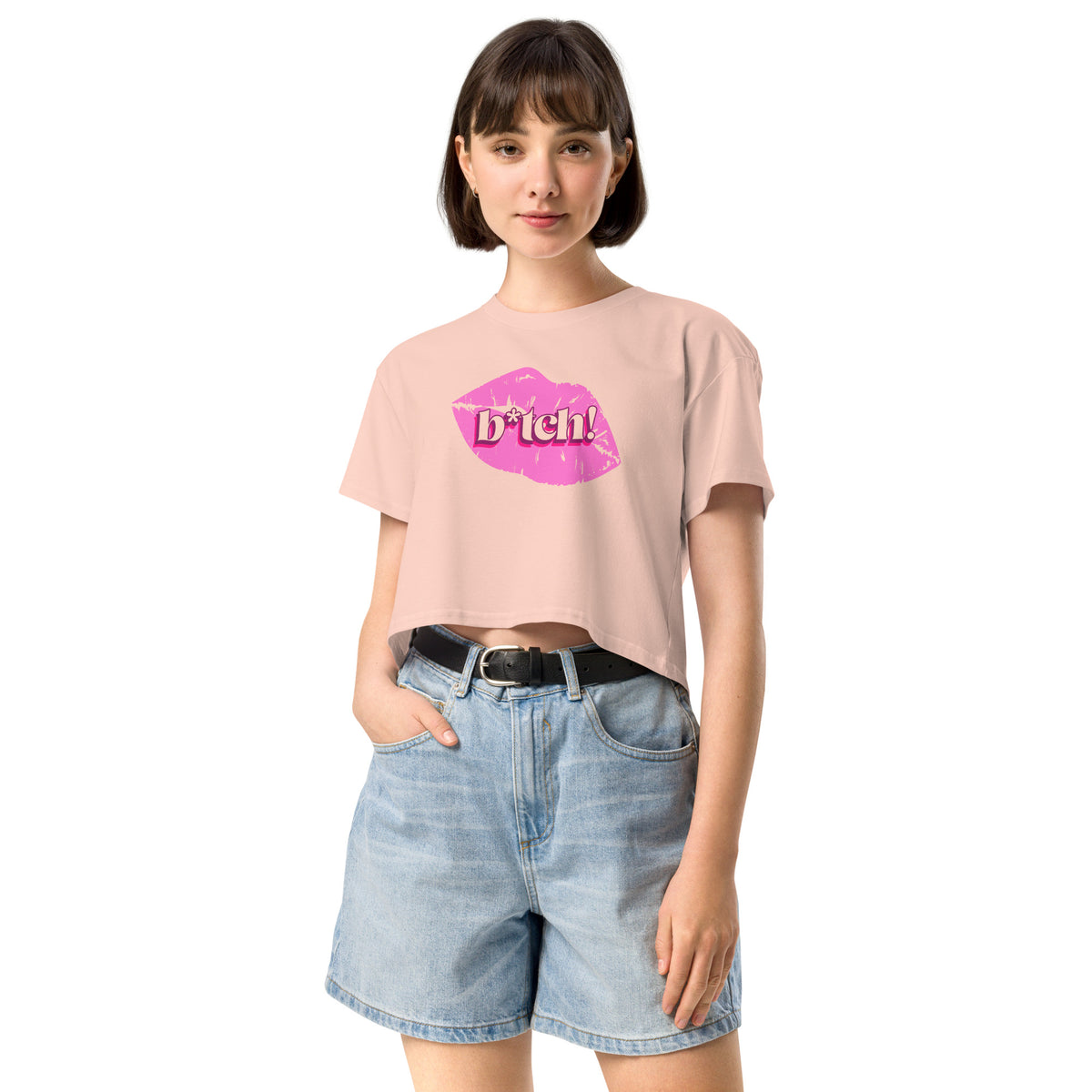 woman wearing a pink crop t-shirt with a graphic design and denim shorts on a white background