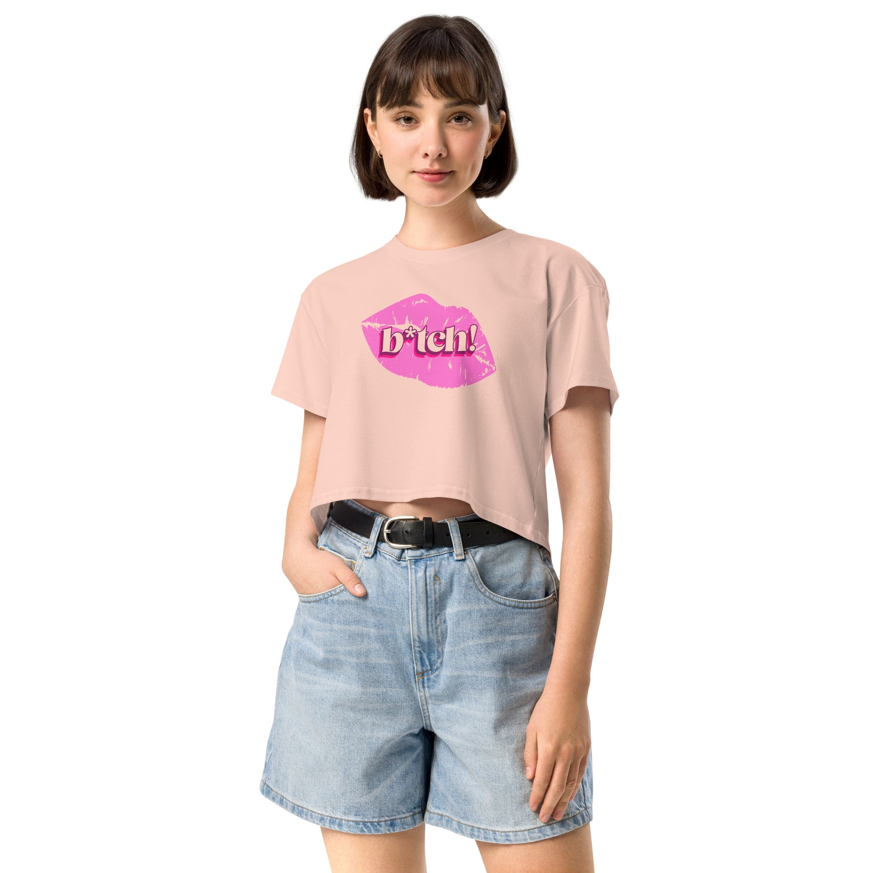 woman wearing a pink crop t-shirt with a graphic design and denim shorts on a white background