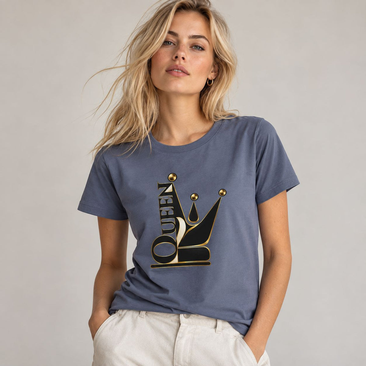 A woman wearing a slate blue crewneck t-shirt with a black and gold graphic of a stylized crown and the word 'QUEEN'.