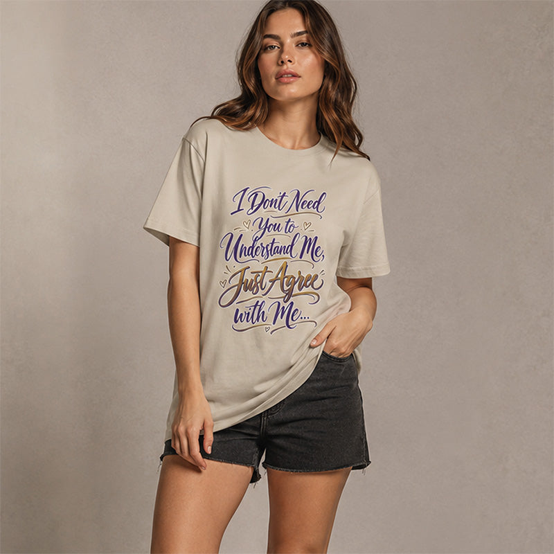 A woman modeling a beige graphic t-shirt with the text 'I Don't Need You to Understand Me, Just Agree with Me.