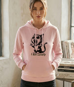 Woman wearing a pink hoodie with a black cat design and 'I Am Lovely' text.