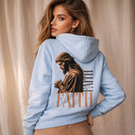 Woman wearing a light blue hoodie with a graphic of a religious figure and the word 'FAITH' on the back.