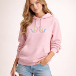 Woman wearing a pink hoodie with colorful designs on a light pink background