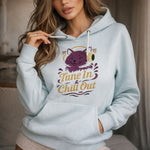 Light blue hoodie with a graphic of a cat wearing headphones and text 'Tune In & Chill Out' worn by a person.