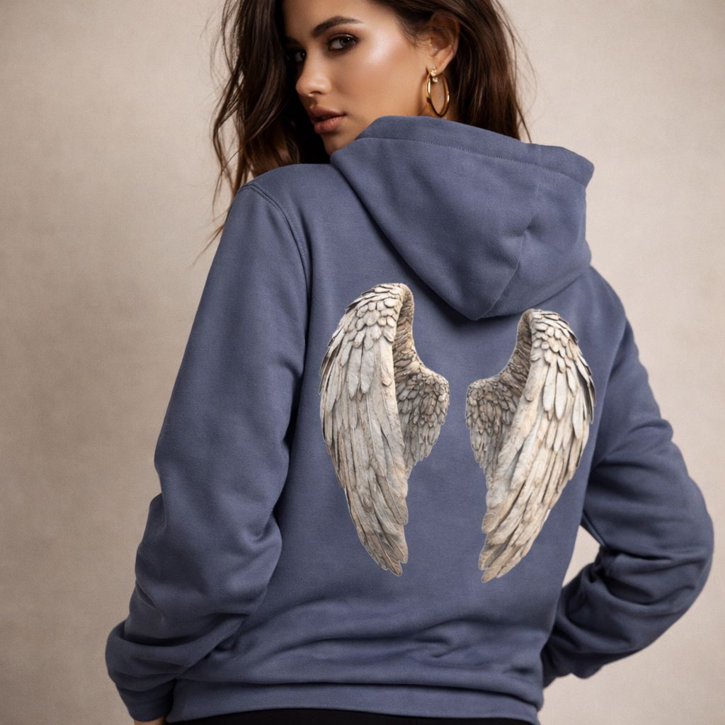 Woman wearing a blue hoodie with angel wings on the back against a beige background