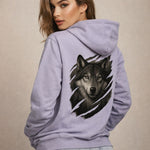 Woman wearing a light purple hoodie with a wolf design on the back against a beige background