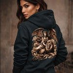 Woman wearing a black hoodie with an angel and lion design on the back against a neutral background