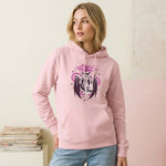 Woman wearing a pink hoodie with a graphic design, standing against a light-colored wall.
