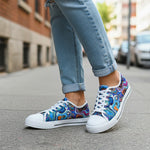 Colorful sneakers worn with blue jeans on a street.