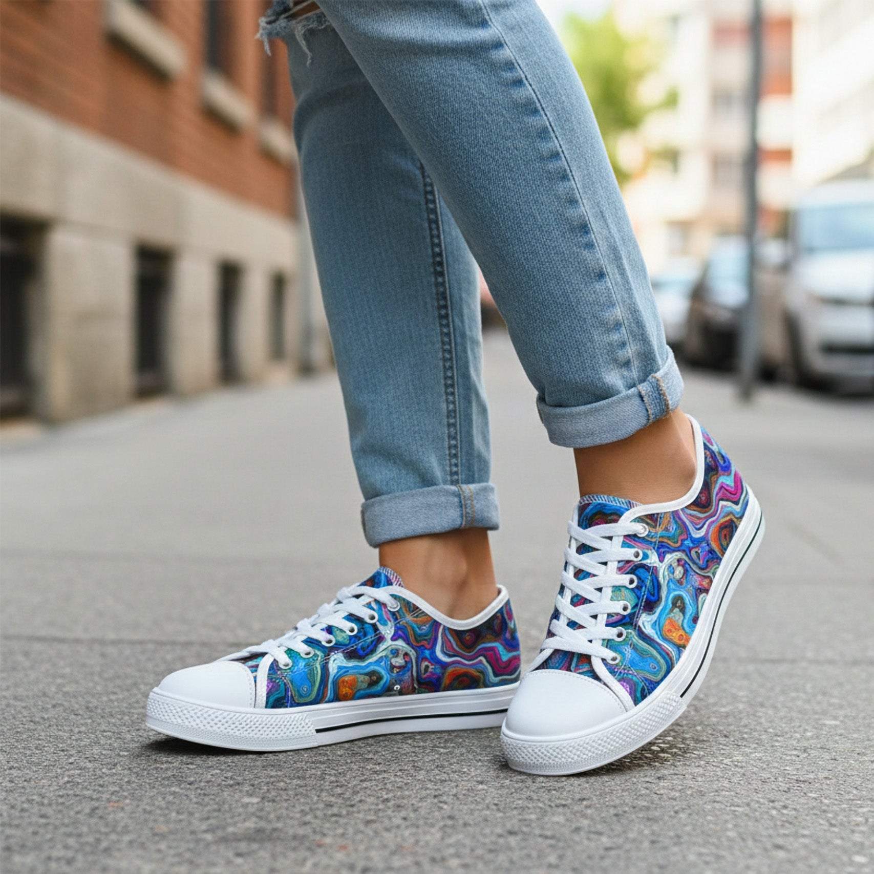 Colorful sneakers worn with blue jeans on a street.