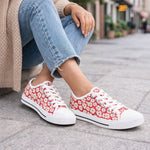 Red floral womens sneakers worn with light blue jeans on a city street.