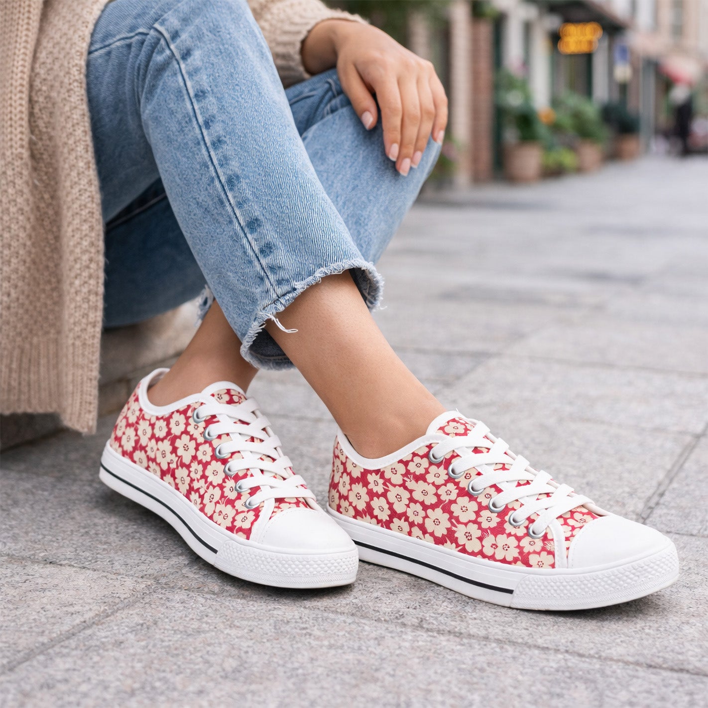 Red floral womens sneakers worn with light blue jeans on a city street.