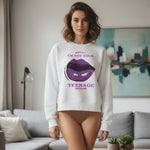 A woman stands indoors wearing a white sweatshirt with a graphic of large purple lips and the text "Sorry I'm not your TEENAGE DREAM," paired with nude underwear. A modern living room is visible in the background.