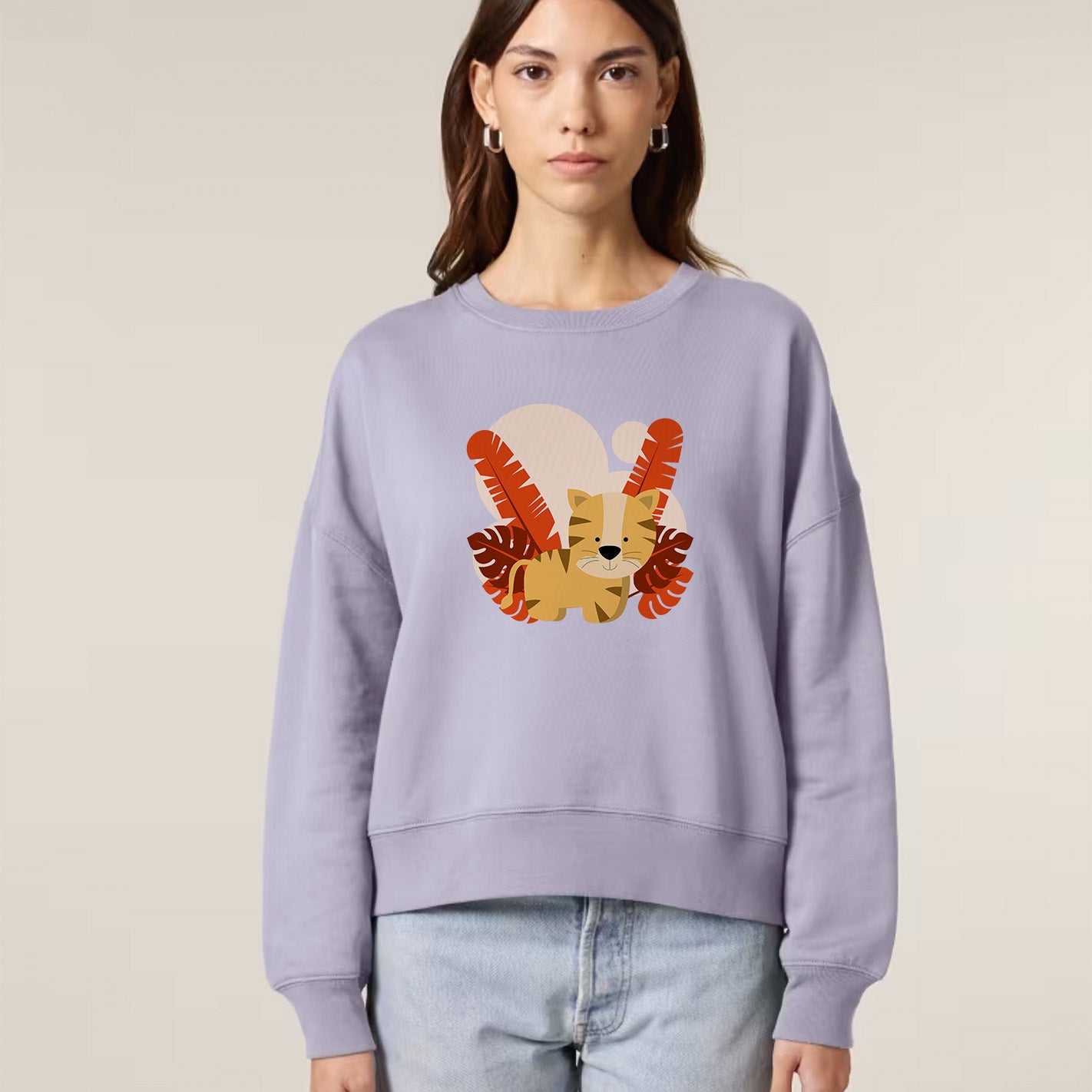woman wearing a light purple sweatshirt with a colorful lion graphic on a beige background