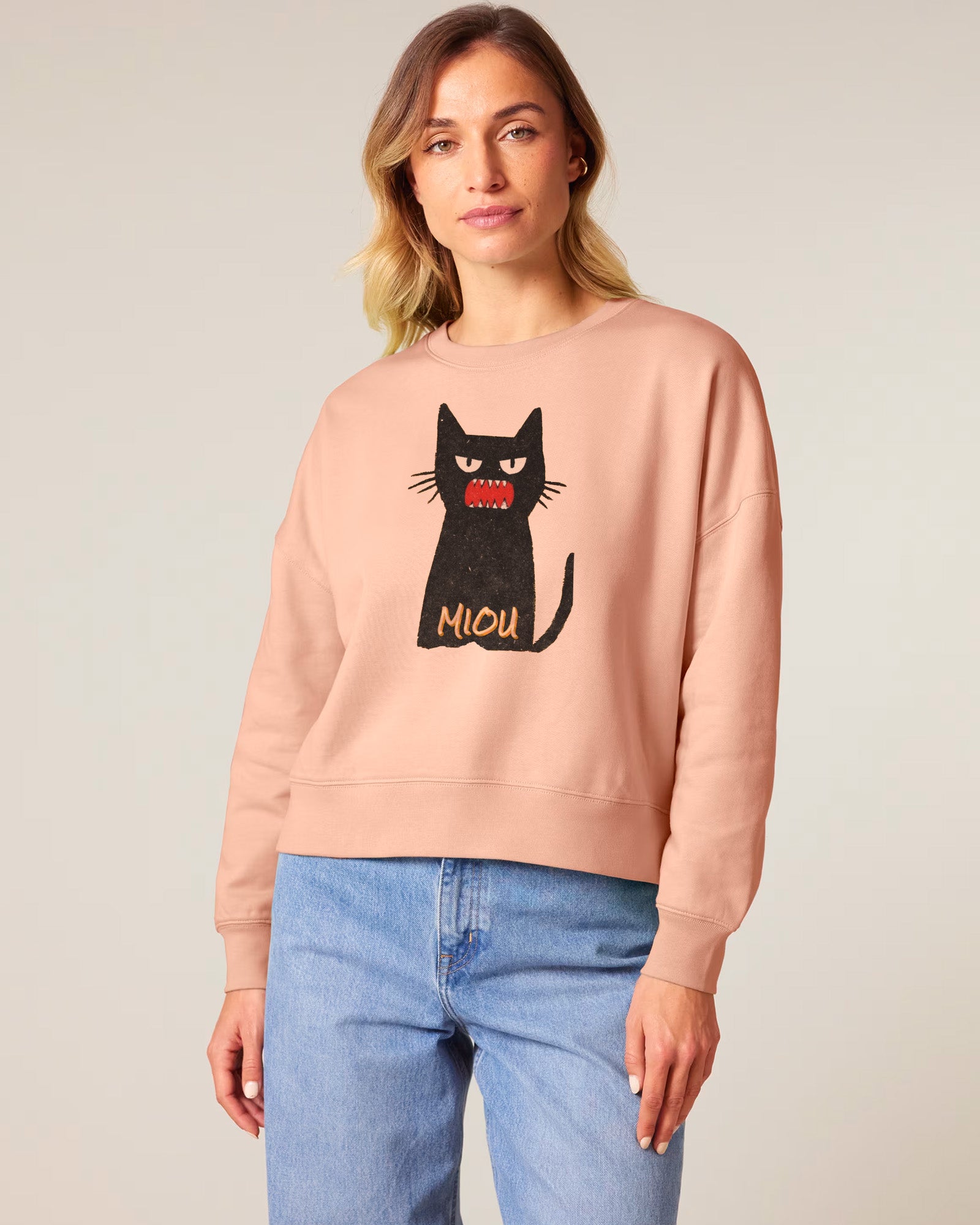Woman wearing a pink sweatshirt with a black cat graphic and 'Miou' text on a plain background