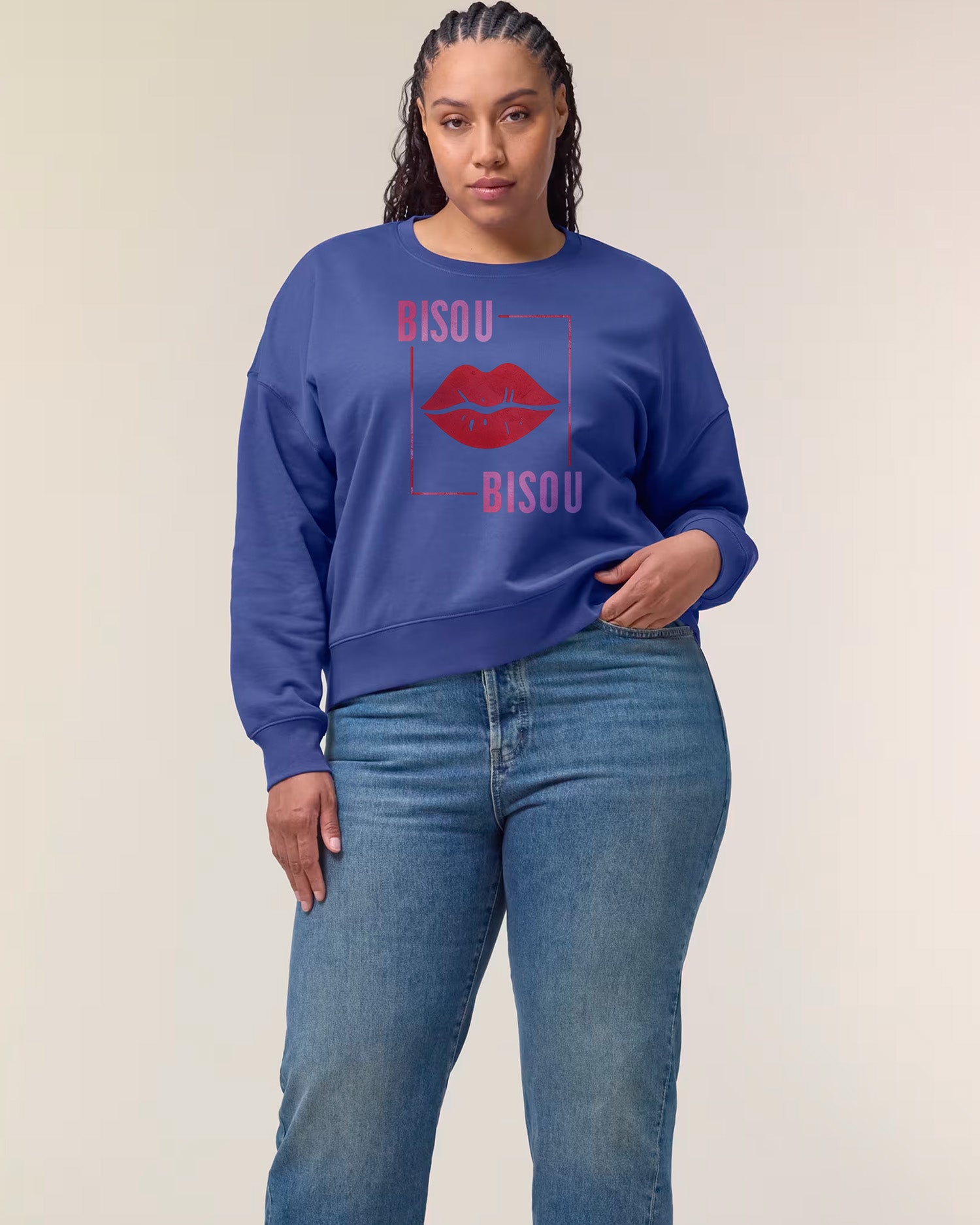 Woman wearing a blue sweatshirt with 'Bisou' text and red lips graphic on a beige background