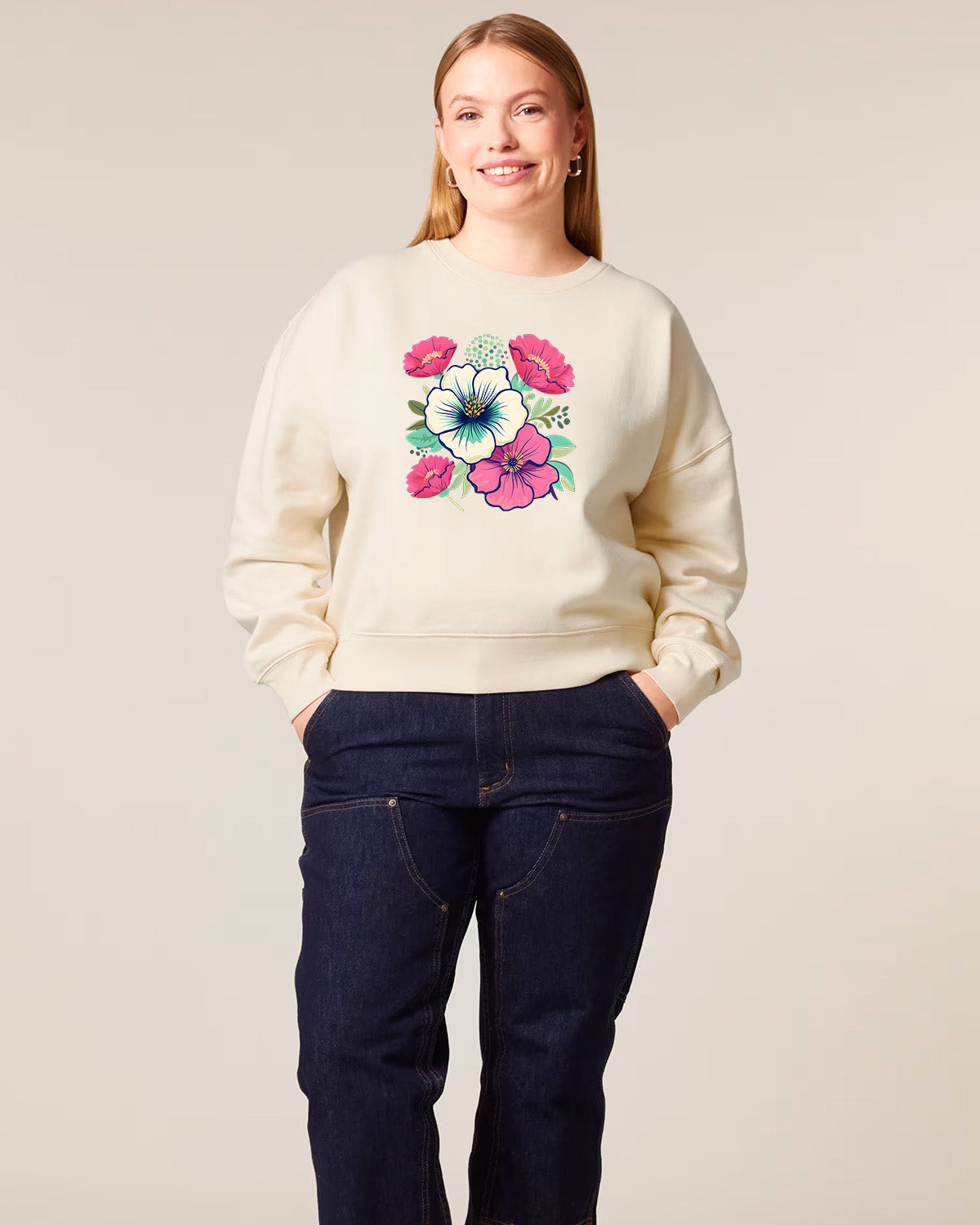 Woman wearing a cream sweatshirt with floral design on a plain background