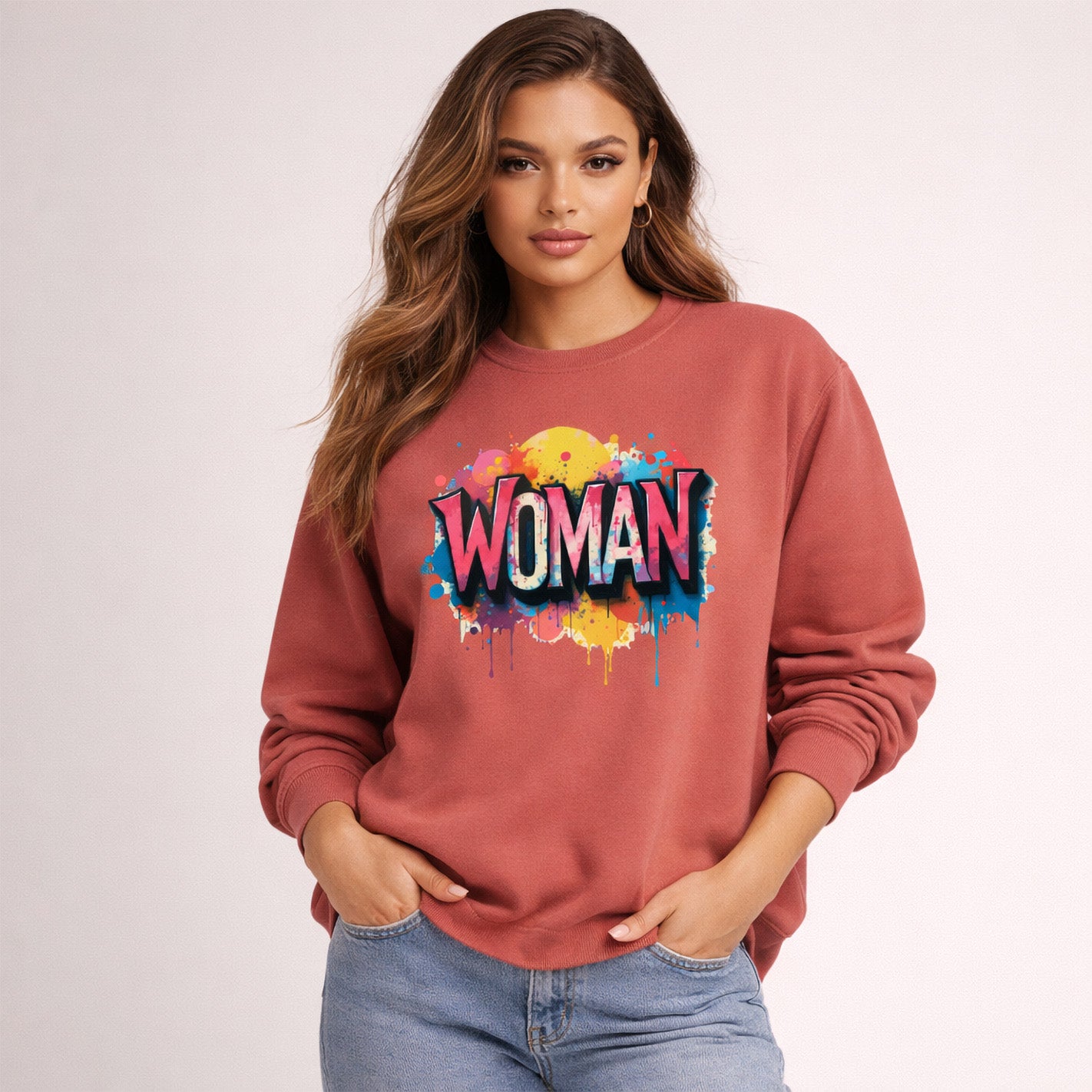 Woman wearing a red sweatshirt with 'WOMAN' in colorful letters on a light pink background