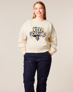 woman wearing a cream sweatshirt with 'Keep Scrolling' text design on a plain background