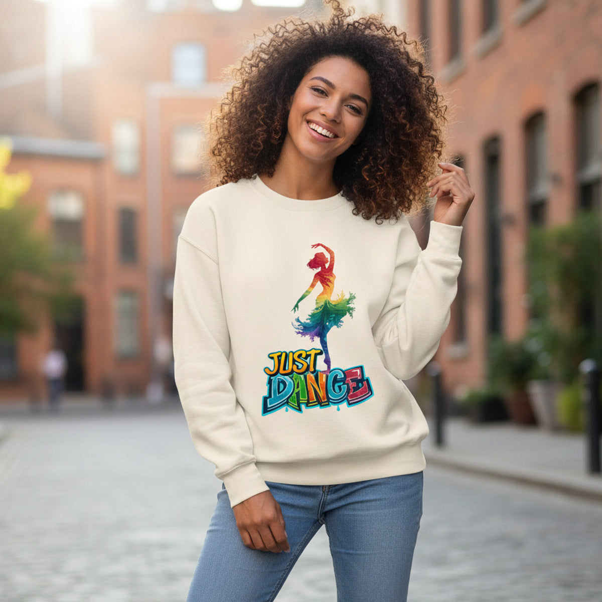 Woman wearing a cream sweatshirt with a colorful 'Just Dance' graphic on a city street.