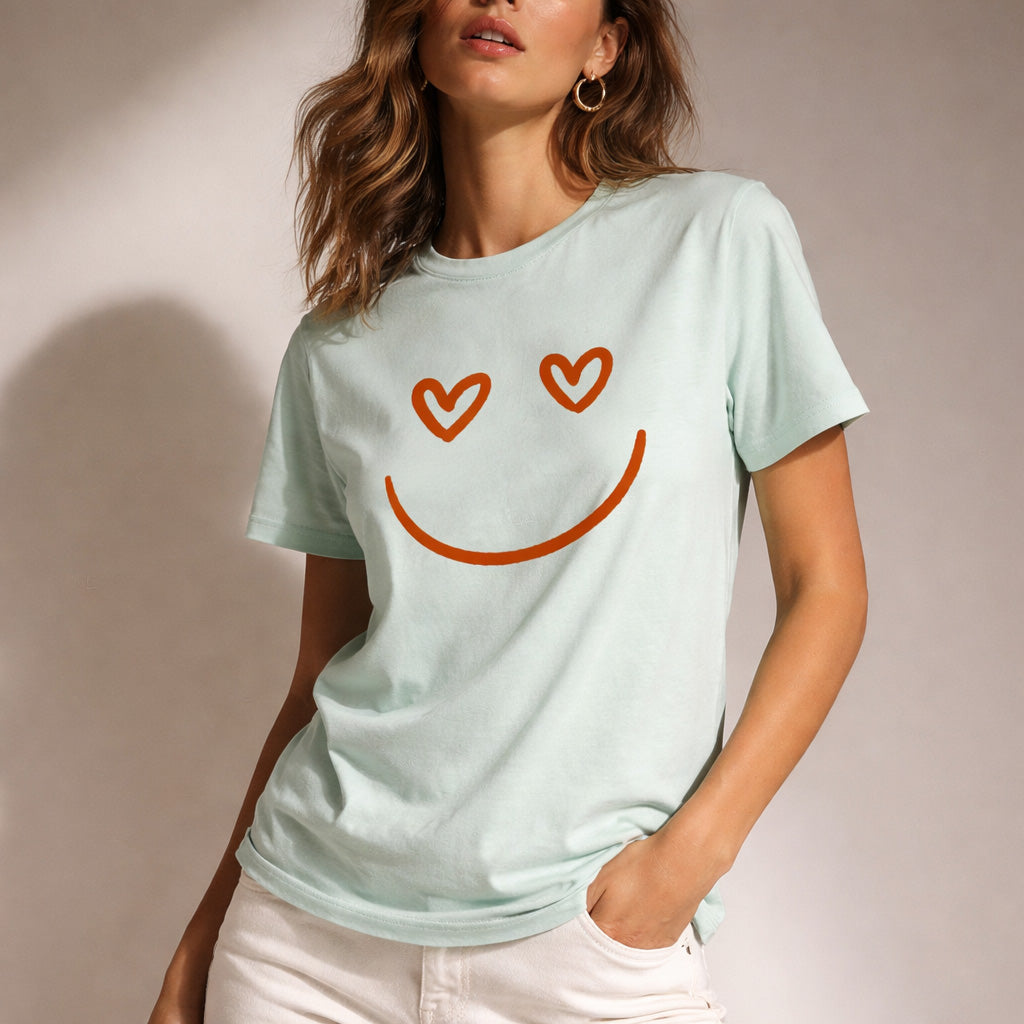 Woman wearing a light blue t-shirt with a smiley face design on a plain background