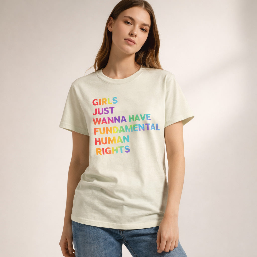 A woman wearing a light-colored T-shirt with the text "Girls just wanna have fundamental human rights" printed in multicolored letters, standing against a neutral background.