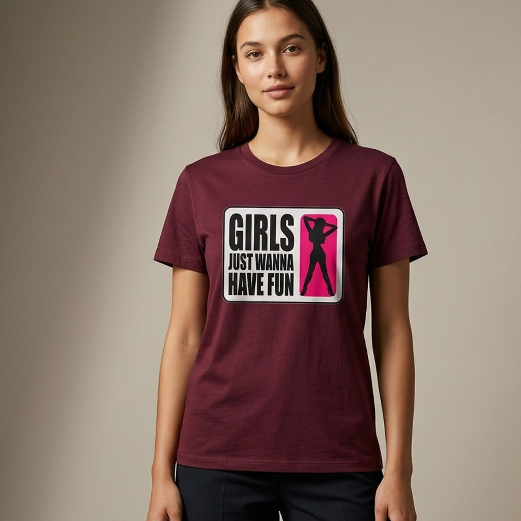 A woman wearing a maroon T-shirt with a graphic that reads "Girls Just Wanna Have Fun" and features a pink silhouette of a dancing woman. She stands against a neutral background, facing the camera.