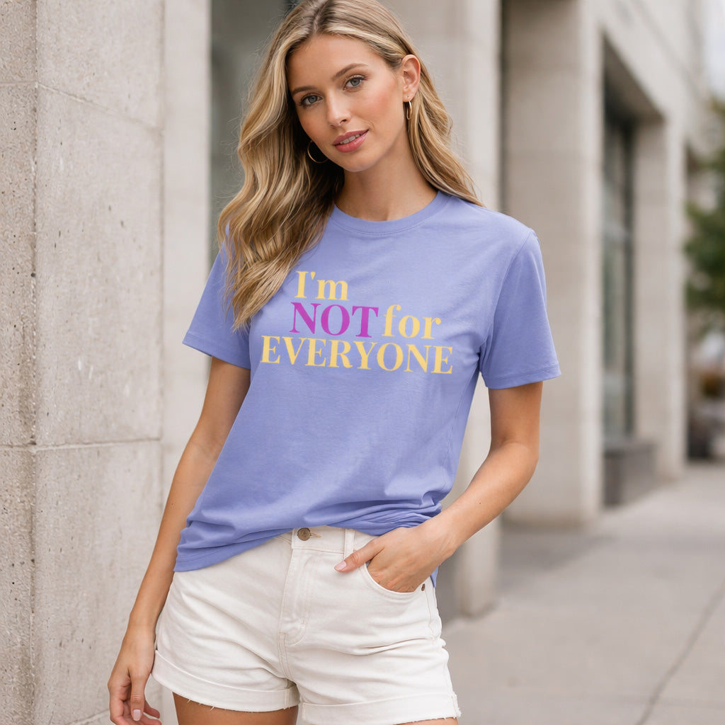 Woman wearing a purple t-shirt with text standing against a building.