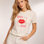 Woman wearing a white t-shirt with 'Bisou Bisou' design on a plain background
